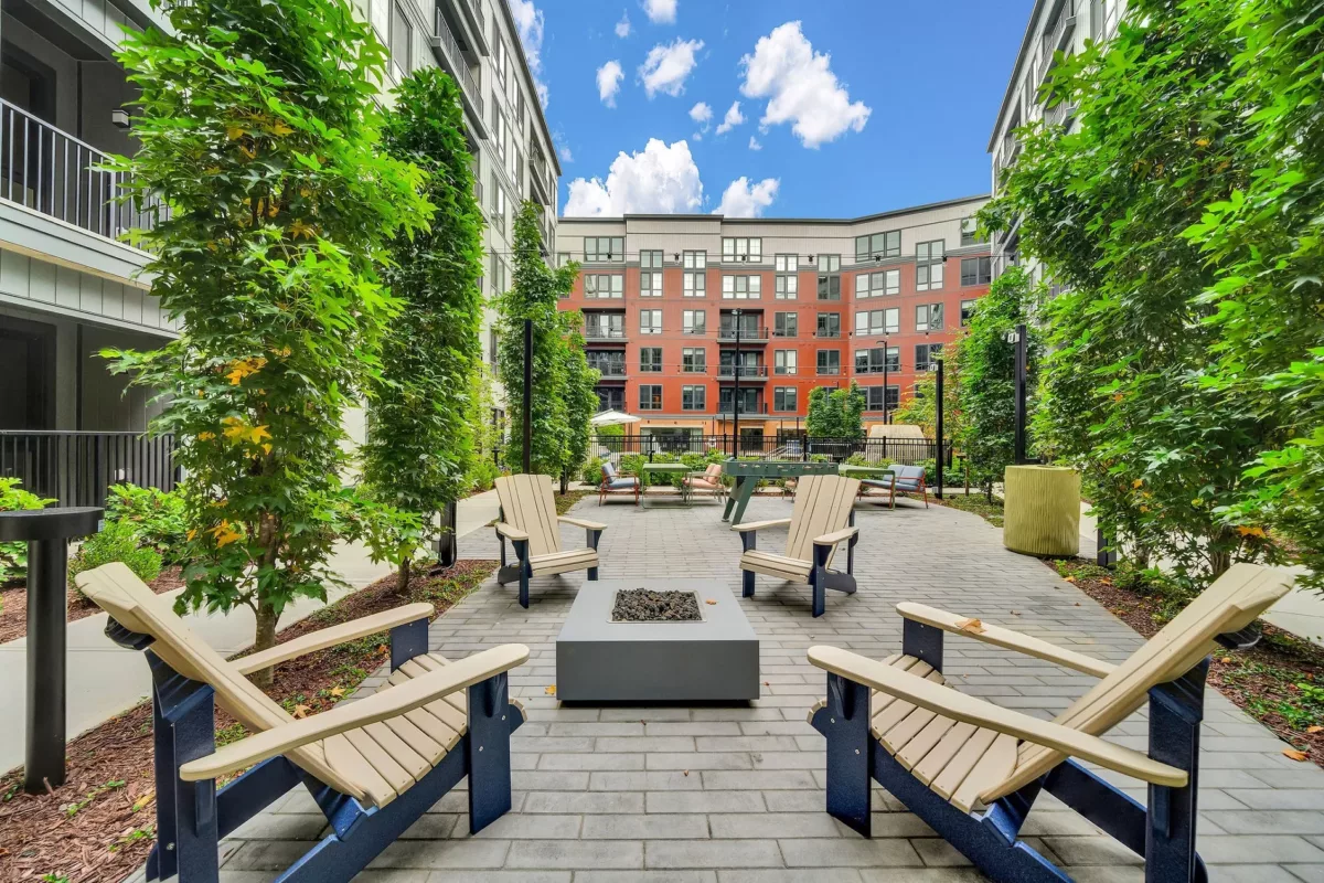 Outdoor courtyard with Adirondack chairs, fire pit, and foosball table between apartment buildings.