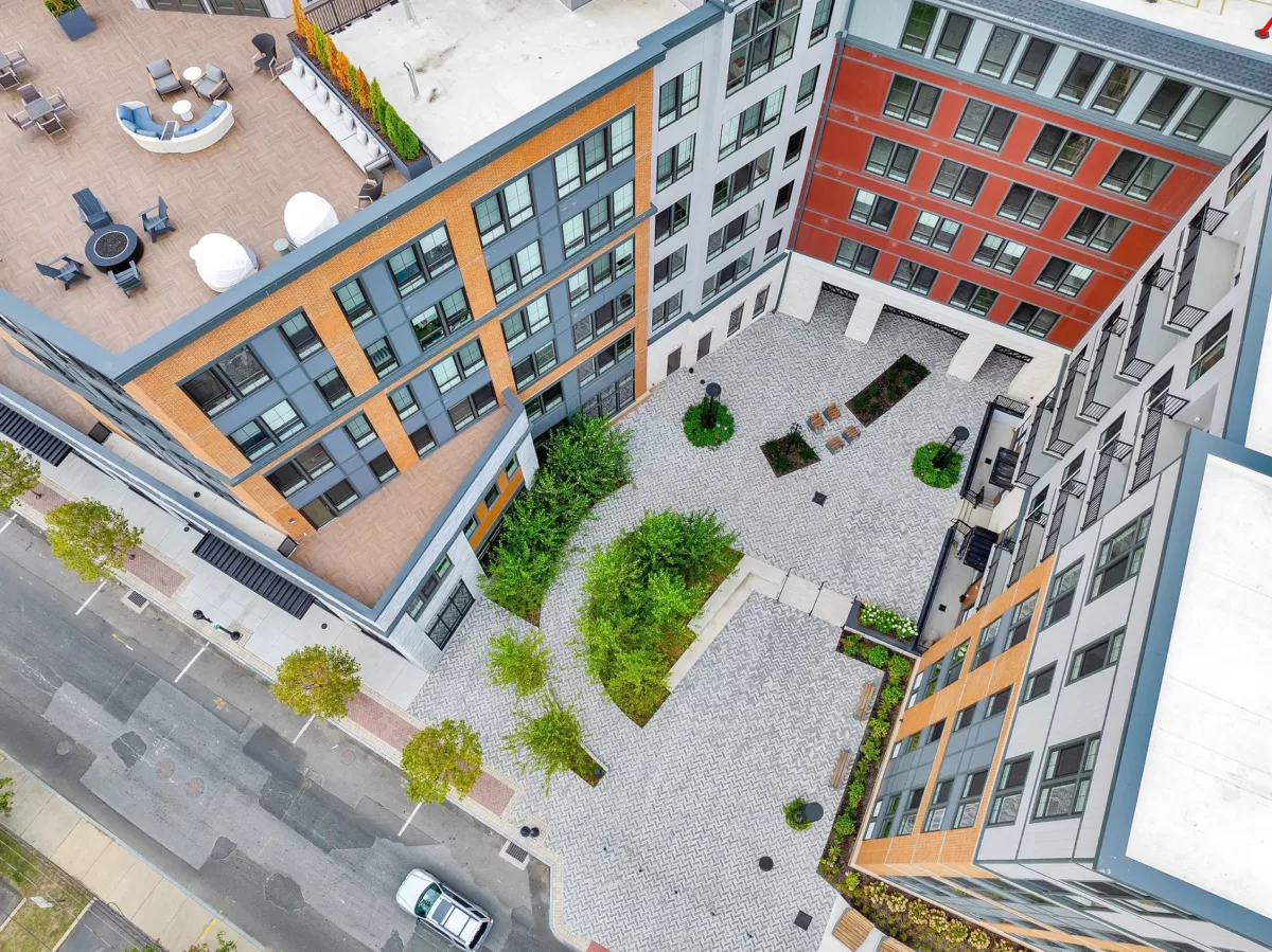 Aerial view of multi-story buildings surrounding a landscaped courtyard with seating and walkways.