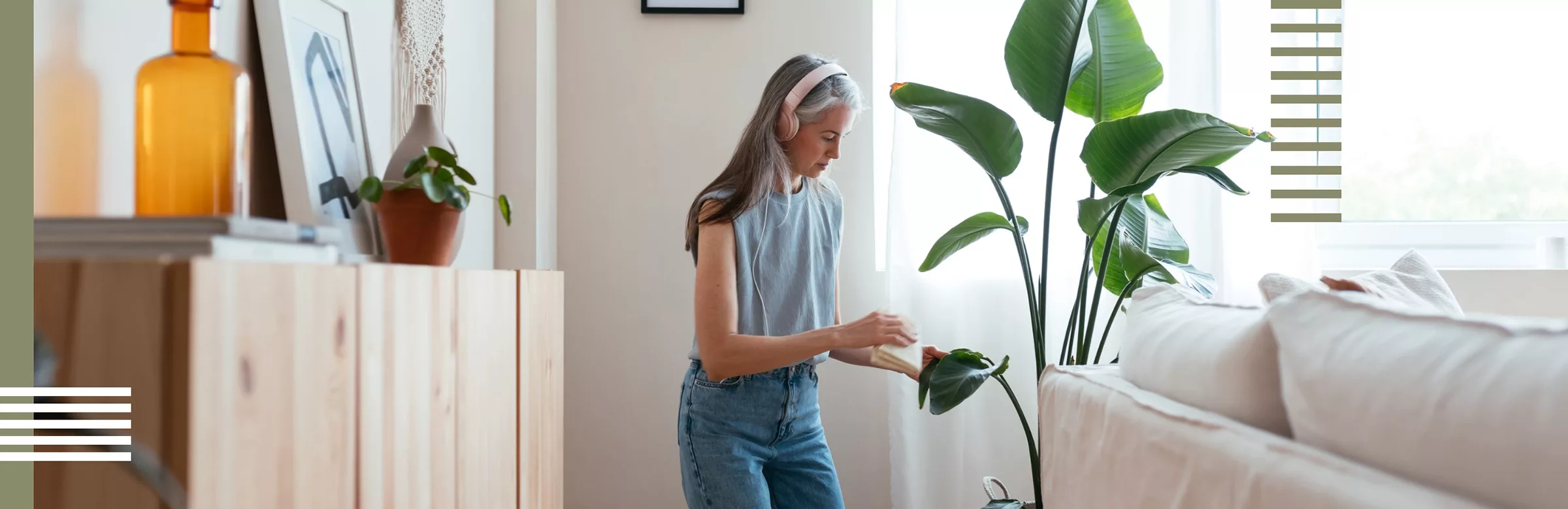 Woman tending to a plant in a well-lit, minimalist living space with natural elements.